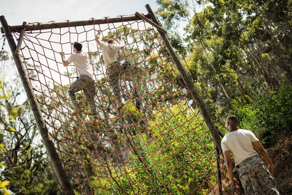 Military soldiers climbing rope during obstacle course — Stock Photo, Image