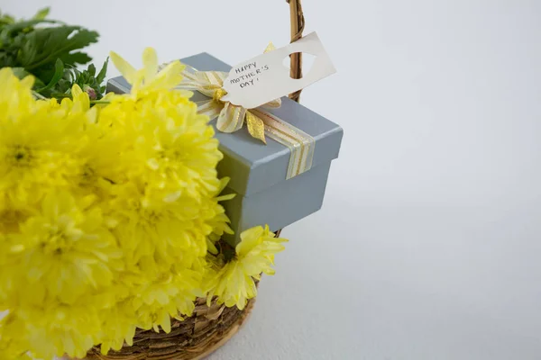 Gift box and bunch of yellow flowers in wicker basket with happy mothers day tag — Stock Photo, Image