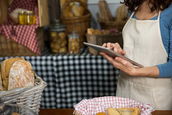 Bagian tengah dari staf yang menggunakan tablet digital di konter toko roti — Stok Foto