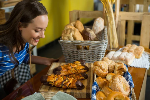 Smiling woman smelling a bakery snacks at counter — Stock Photo, Image