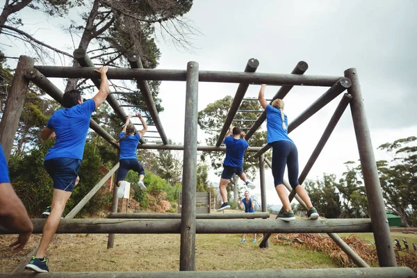 Fitte Menschen klettern im Bootcamp auf Affenstangen — Stockfoto