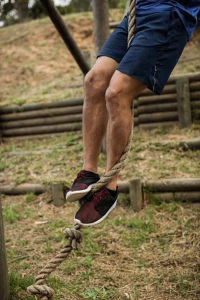 Sección baja del hombre escalando una cuerda durante la carrera de obstáculos — Foto de Stock