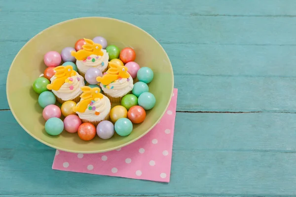 Chocolates coloridos y cupcakes en un tazón — Foto de Stock