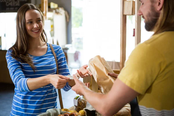 Lächelnde Kundin bezahlt Rechnung bar an der Brottheke — Stockfoto