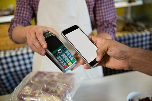 Mid sectie van man betalen via nfc technologie aan balie — Stockfoto