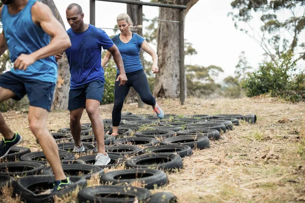 Personas que reciben formación en carrera de obstáculos neumáticos —  Fotos de Stock