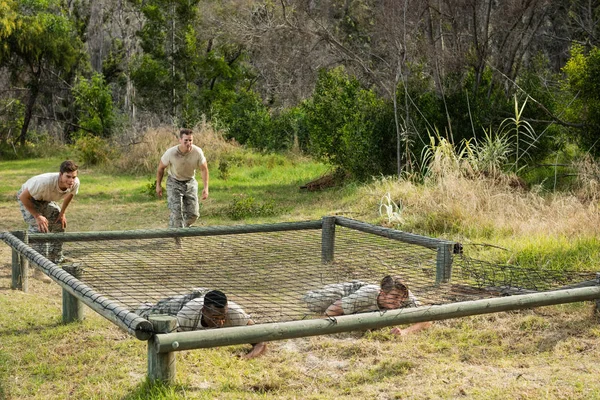 Soldaten onder het net kruipen tijdens hindernissenparcours — Stockfoto