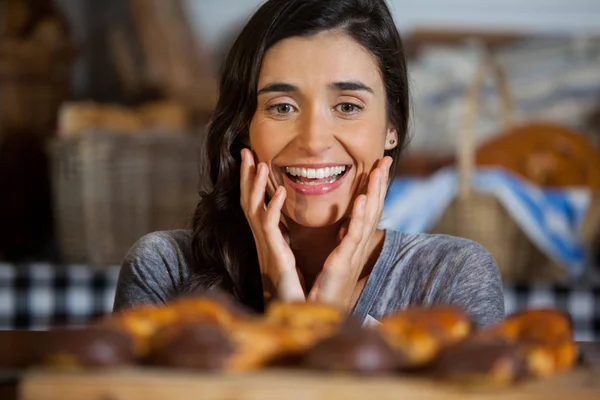 Mulher sorridente olhando para pães no balcão — Fotografia de Stock