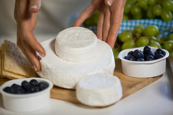 Hands of female staff arranging cheese at counter — Stock Photo, Image