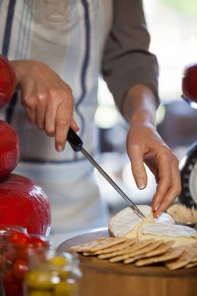 Sección media del personal femenino rebanando queso en el mostrador — Foto de Stock