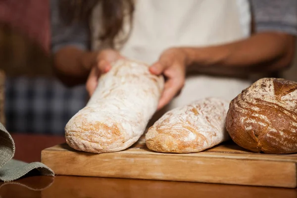 Mid-section of woman holding bread at counter — Stock Photo, Image