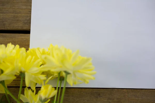 Fiori gialli con busta su tavola di legno — Foto Stock