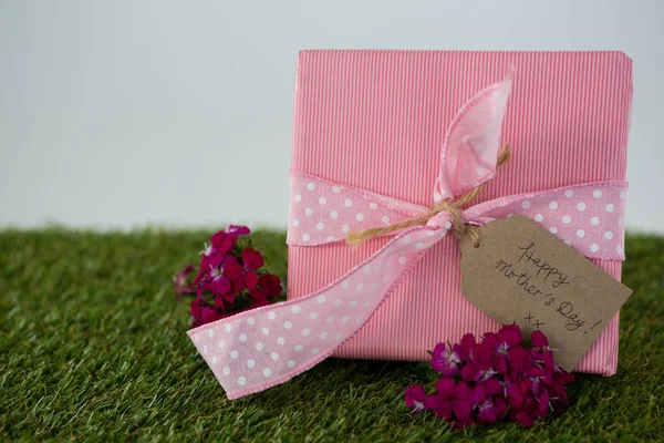 Mutlu anne günü etiketi ve çimlerin üzerine çiçek hediye kutusu — Stok fotoğraf
