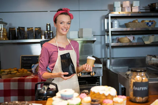 Portrait du personnel féminin tenant un sac à café et une tasse de café au comptoir — Photo