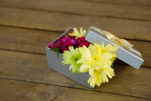 Caixa de presente com flores na superfície de madeira — Fotografia de Stock