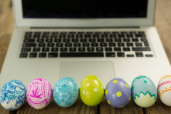 Painted Easter eggs and laptop on wooden surface — Stock Photo, Image