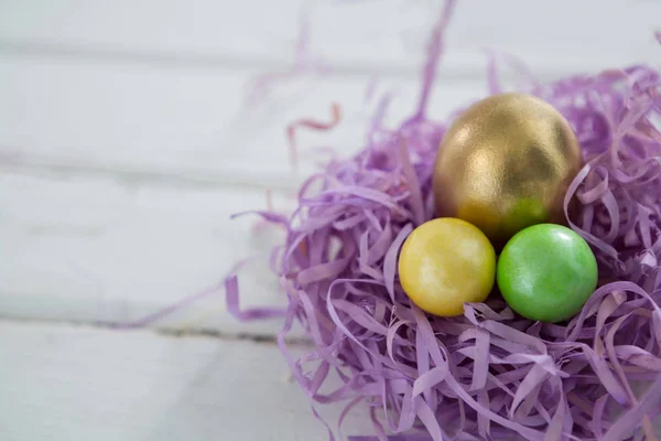 Gyllene påskägg med två målade ägg i boet — Stockfoto