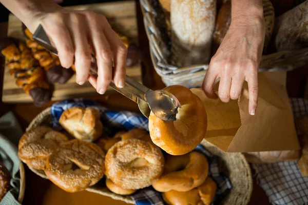 Mid sectie vanpersoneel donut verpakking in papieren zak aan balie — Stockfoto