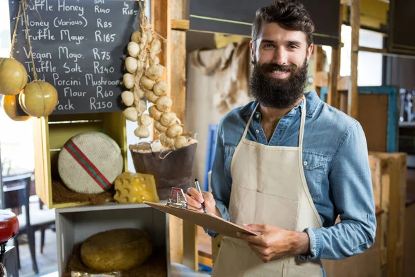 Salesman writing on clipboard at counter in grocery shop in market — Stock Photo, Image