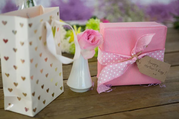 Geschenktüte, Geschenkbox und Blumenvase auf Holzoberfläche — Stockfoto