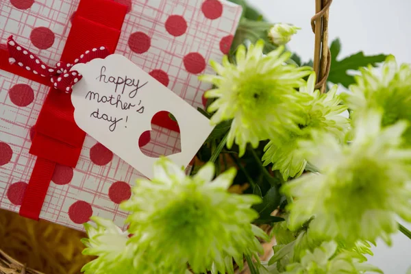 Caixa de presente e um monte de flores amarelas em cesta de vime com feliz mãe dia tag — Fotografia de Stock