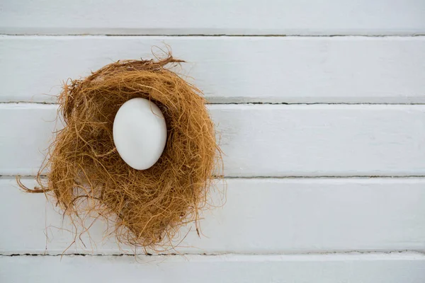 Ovo branco no ninho na superfície de madeira — Fotografia de Stock