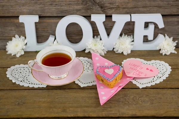 Galletas, té, flores y feliz tarjeta de día de las madres con texto de amor —  Fotos de Stock