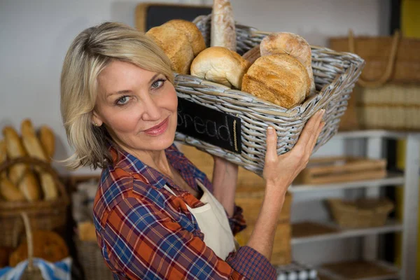 여성 직원 카운터에서 다양 한 빵의 바구니를 들고 미소의 초상화 — 스톡 사진