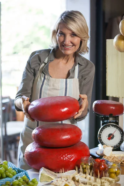 Portrait of female staff holding gouda cheese at counter — Stock Photo, Image