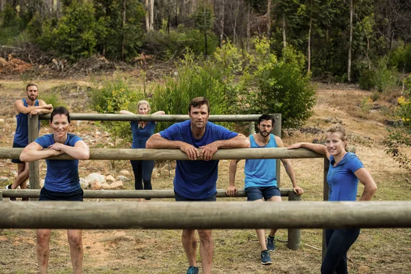 Grupo de pessoas que se apoiam em obstáculos durante o treinamento de obstáculos — Fotografia de Stock