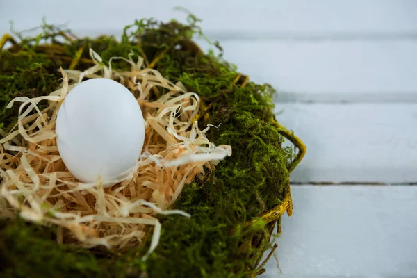 Beyaz ahşap yüzeyde yuvadaki yumurta — Stok fotoğraf