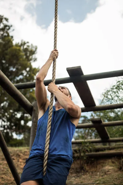 Fit man climbing a rope during obstacle course — Stock Photo, Image