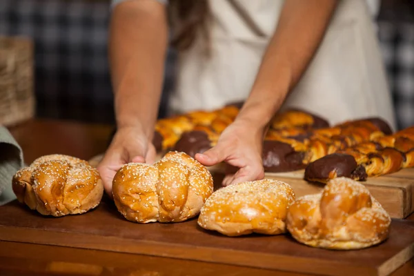 Mid-section of woman holding bread at counter — Stock Photo, Image