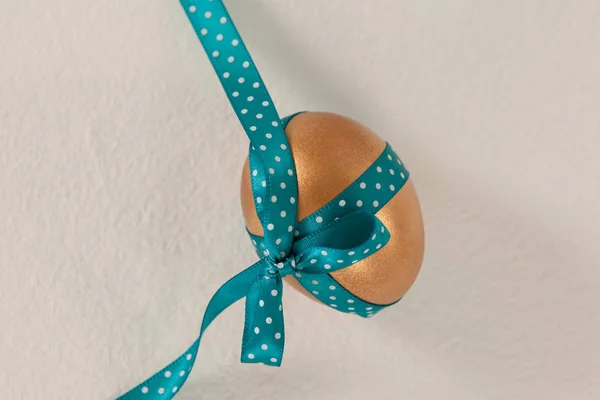 Zlaté velikonoční vajíčko s modrou stužkou — Stock fotografie