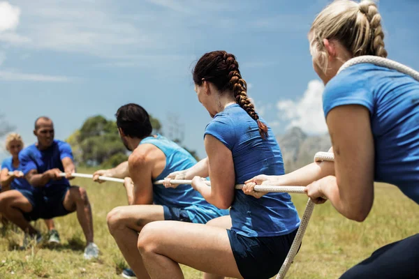 Ludzi grających przeciąganie liny podczas szkolenia z przeszkodami — Zdjęcie stockowe