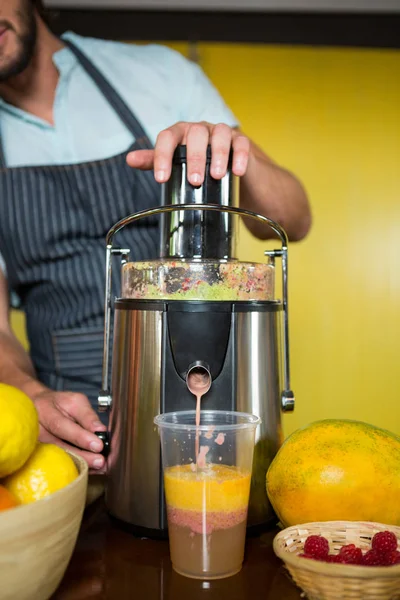 Asistente de tienda preparando zumo de fruta — Foto de Stock