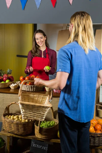 Sorrindo equipe feminina oferecendo frutas para o cliente na seção orgânica — Fotografia de Stock