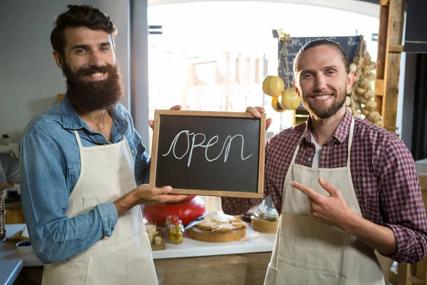 Smiling male staffs holding a open sign — Stock Photo, Image