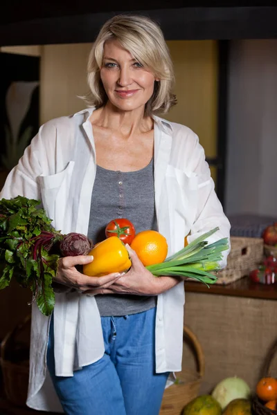 Portrait femme costumière tenant légumes et fruits frais en section bio — Photo