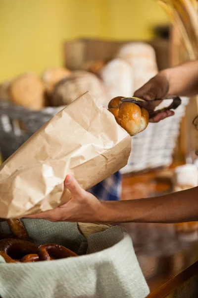 Mitarbeiter packen in Bäckerei Brot in Papiertüte — Stockfoto