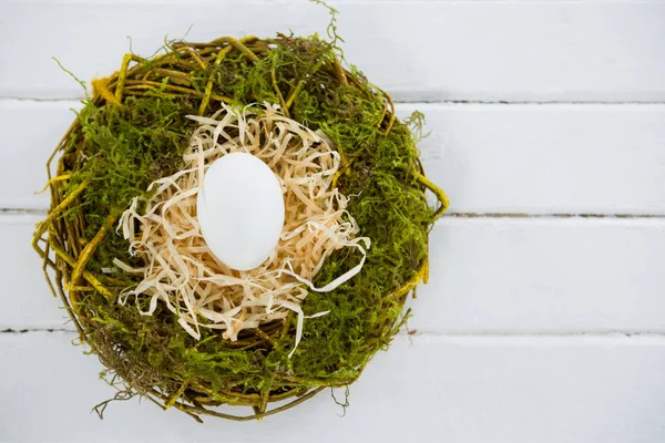 Huevo blanco en el nido en la superficie de madera —  Fotos de Stock
