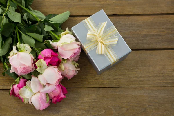 Gift box with bunch of rose on wooden plank — Stock Photo, Image