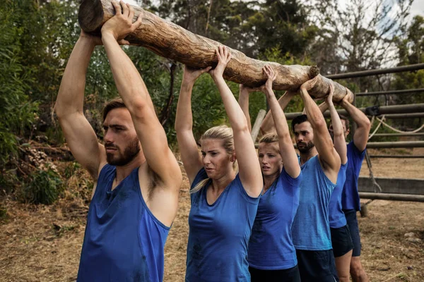 Pessoas levantando um tronco de madeira pesada durante o acampamento — Fotografia de Stock