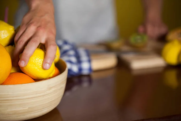 A meio da seção de pessoal masculino pegando uma fruta de limão de uma tigela — Fotografia de Stock