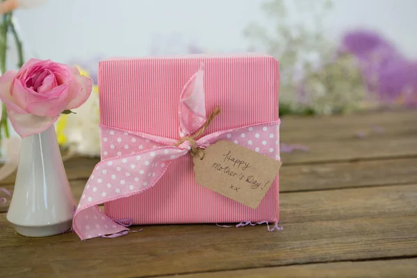 Ahşap yüzey üzerinde hediye kutusu ve çiçek vazo — Stok fotoğraf