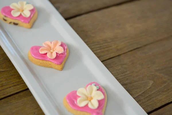 Heart shape cookies in tray on wooden plank — Stock Photo, Image