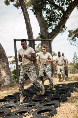 Young military soldiers practicing tyre obstacle course clipart