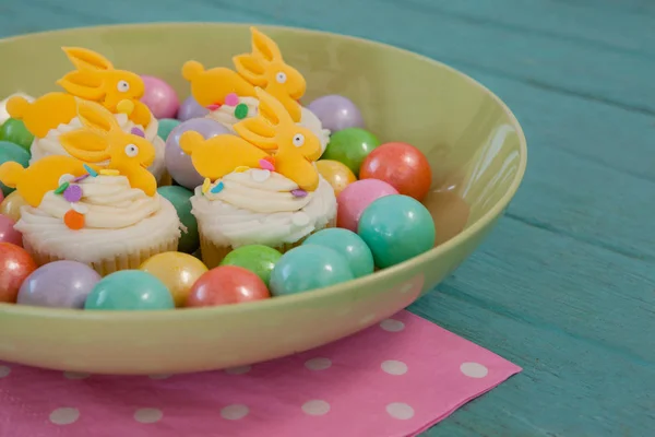 Colorful chocolates and cupcakes in bowl — Stock Photo, Image