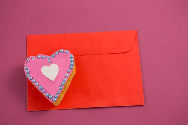 Szív alakú cookie-t a piros borítékot, rózsaszín háttérrel — Stock Fotó