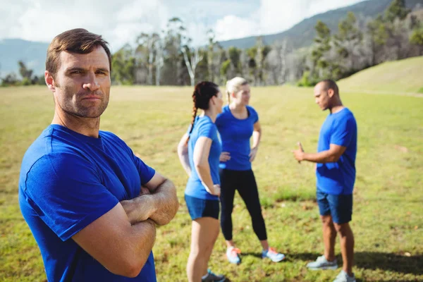 Ajuste hombre de pie con los brazos cruzados en el campo de entrenamiento —  Fotos de Stock